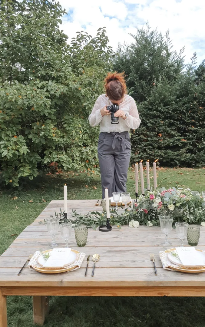 Photo de Elorri prenant en photo sa table décorée pour une mariage avec de la belle vaisselle.